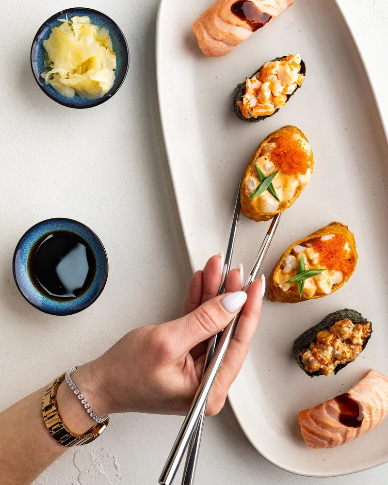 Sushi platter with nigiri and gunkan held with chopsticks at Sushi Icons