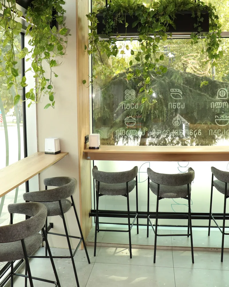 Window counter seating with bar stools and hanging plants at Sushi Icons