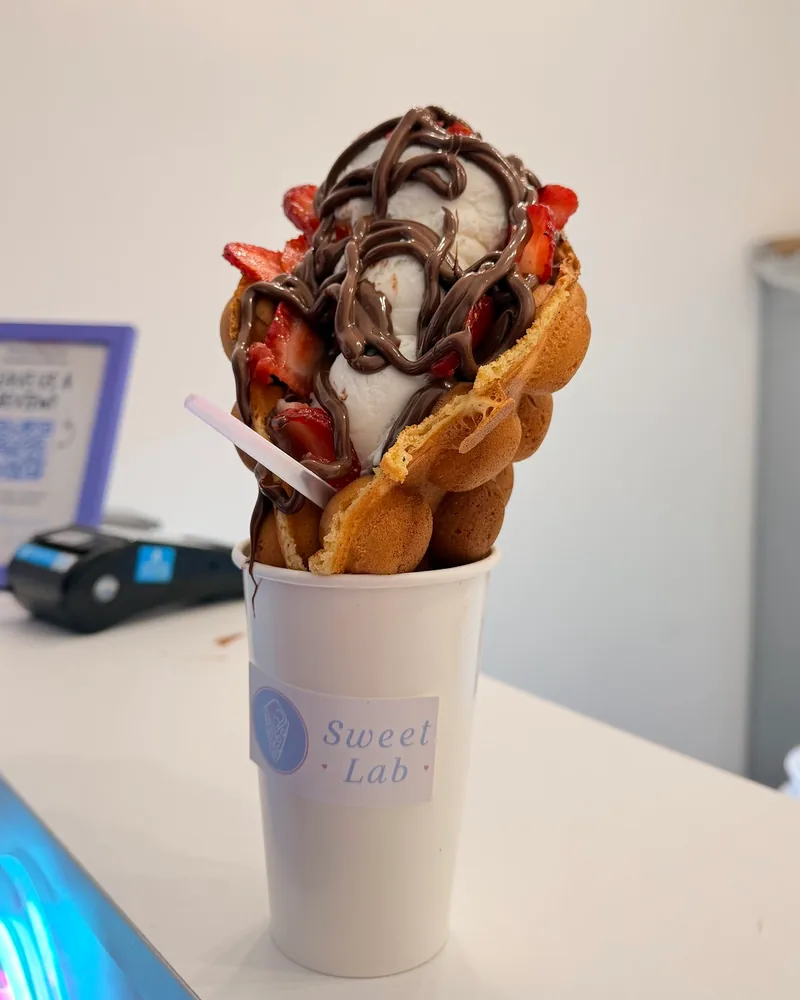 Bubble waffle with ice cream, chocolate drizzle and strawberries at Sweet Lab