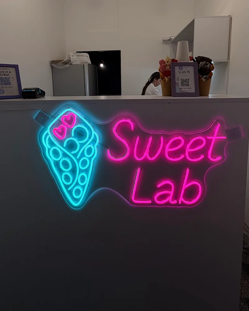 Service counter with a neon Sweet Lab sign at Sweet Lab