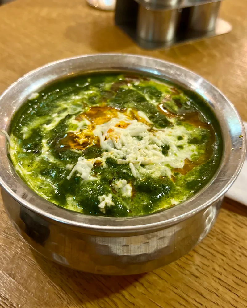 Palak paneer in a stainless steel handi bowl at Taste of India