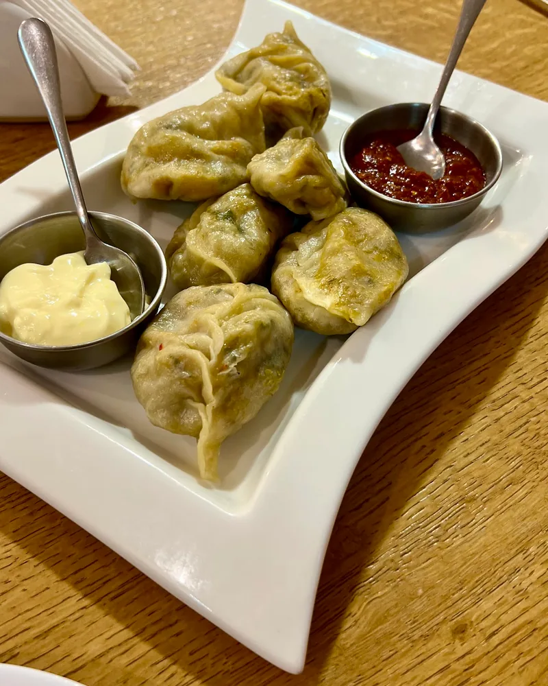 Steamed momos served with white and red dipping sauces at Taste of India