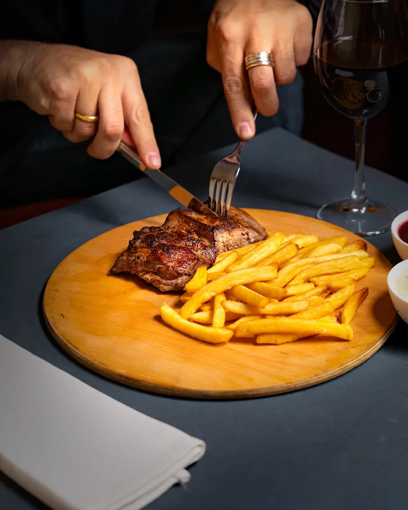 Steak with french fries on a wooden board at Tbili Kera