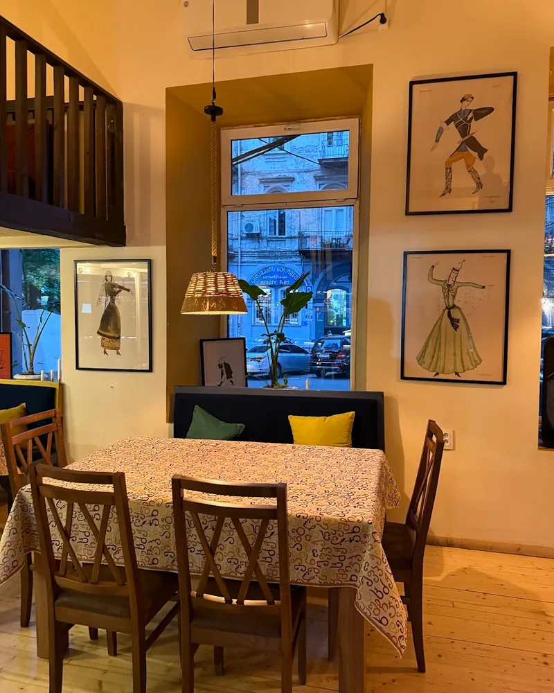 Dining table with patterned tablecloth by a window at Tbili Kera