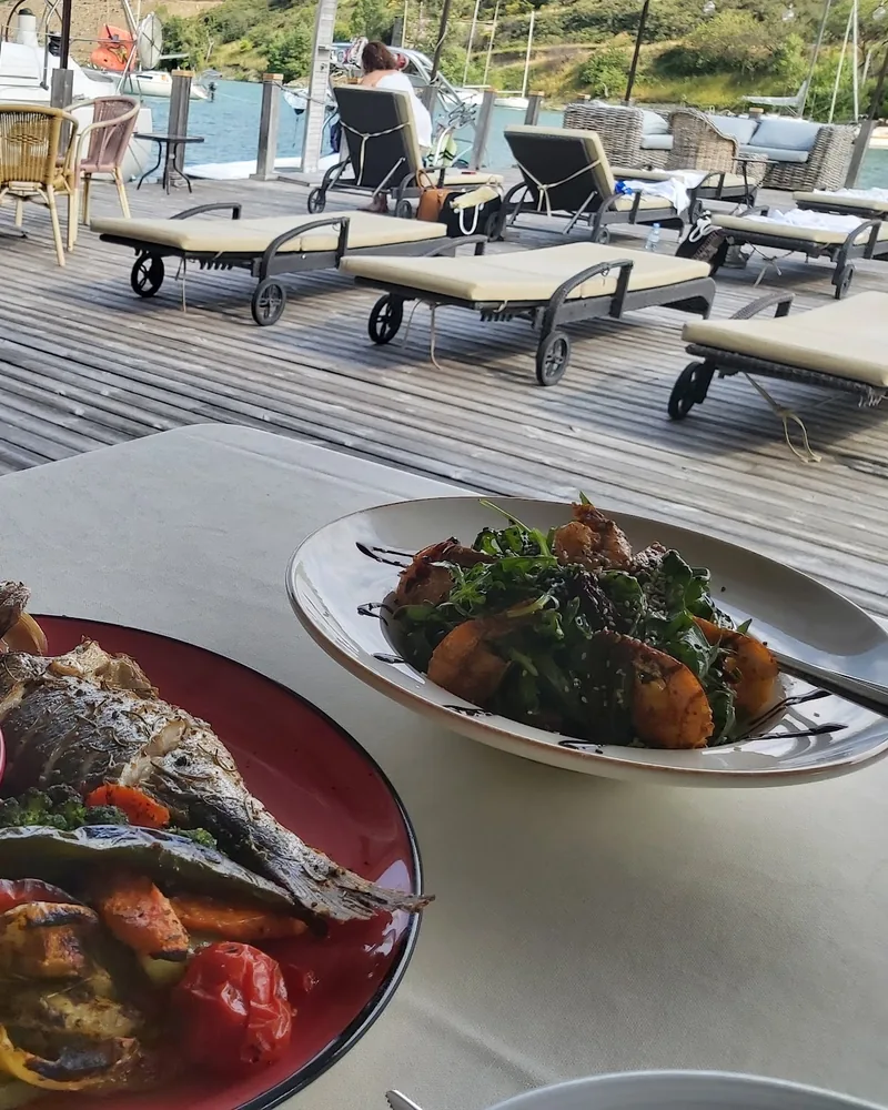 Whole grilled fish with vegetables and salad on a terrace at La Cote