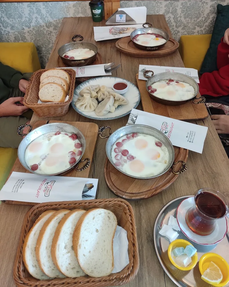 Fried eggs with sausage in pans, khinkali and sliced bread at TbilisIstanbul