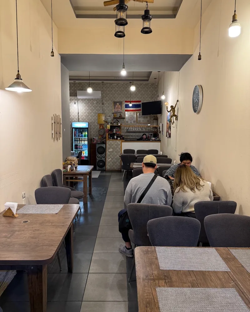 Narrow dining room with wooden tables and grey chairs at Thanapon