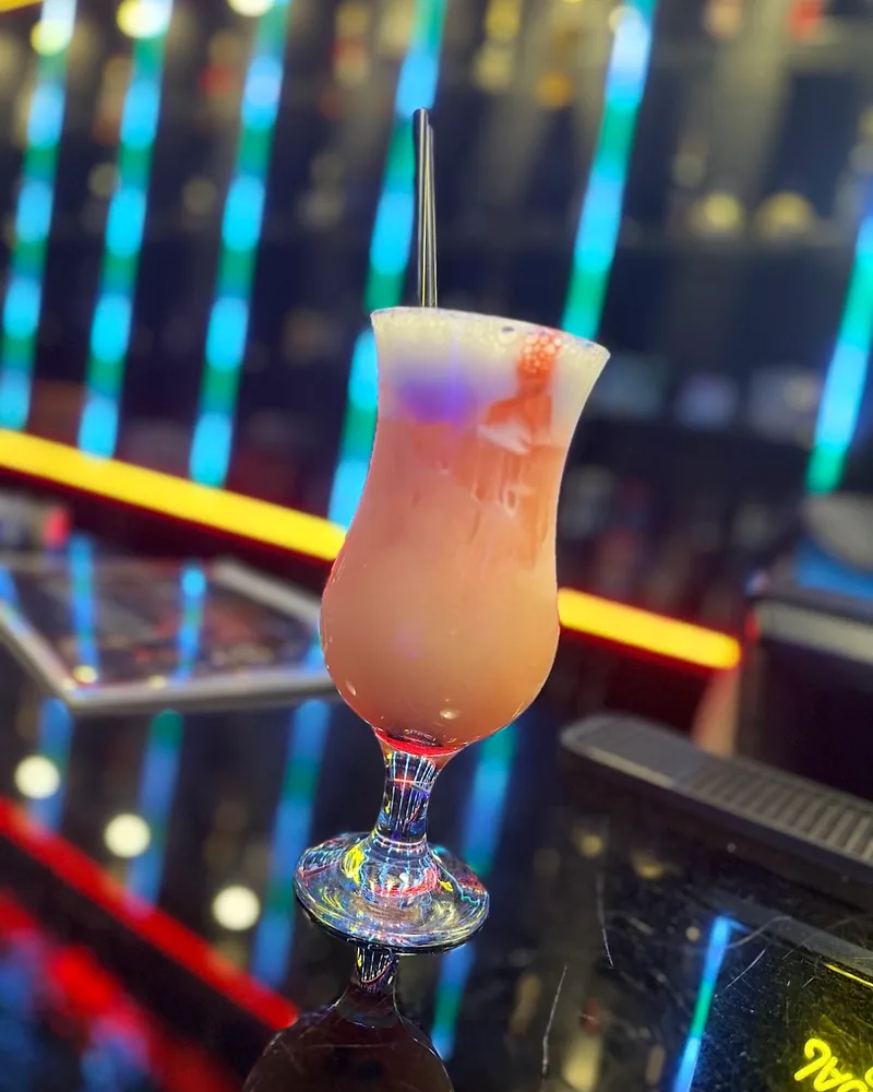 Layered cocktail in a hurricane glass with a straw at The Bank Club