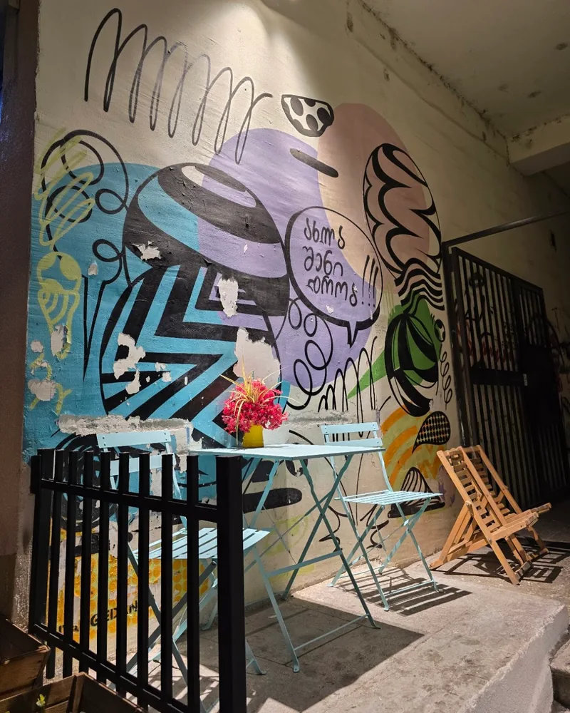 Outdoor patio seating with painted mural wall at The Cone Culture