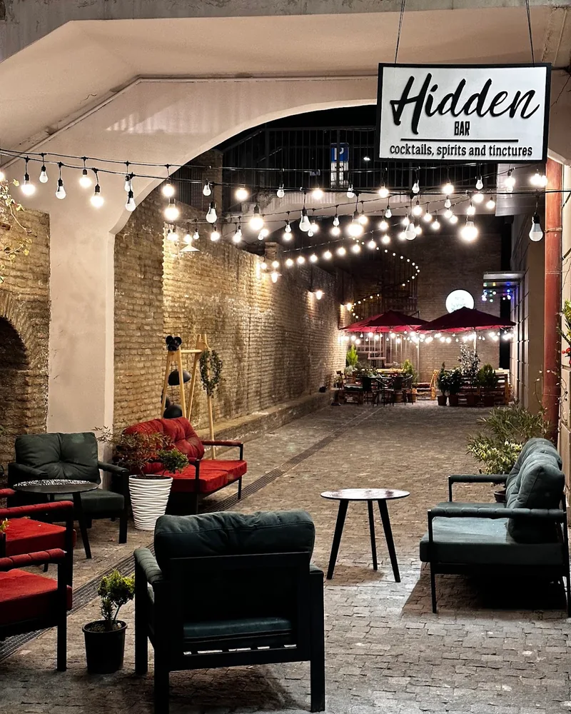 Courtyard patio with string lights and lounge seating at The Hidden Bar