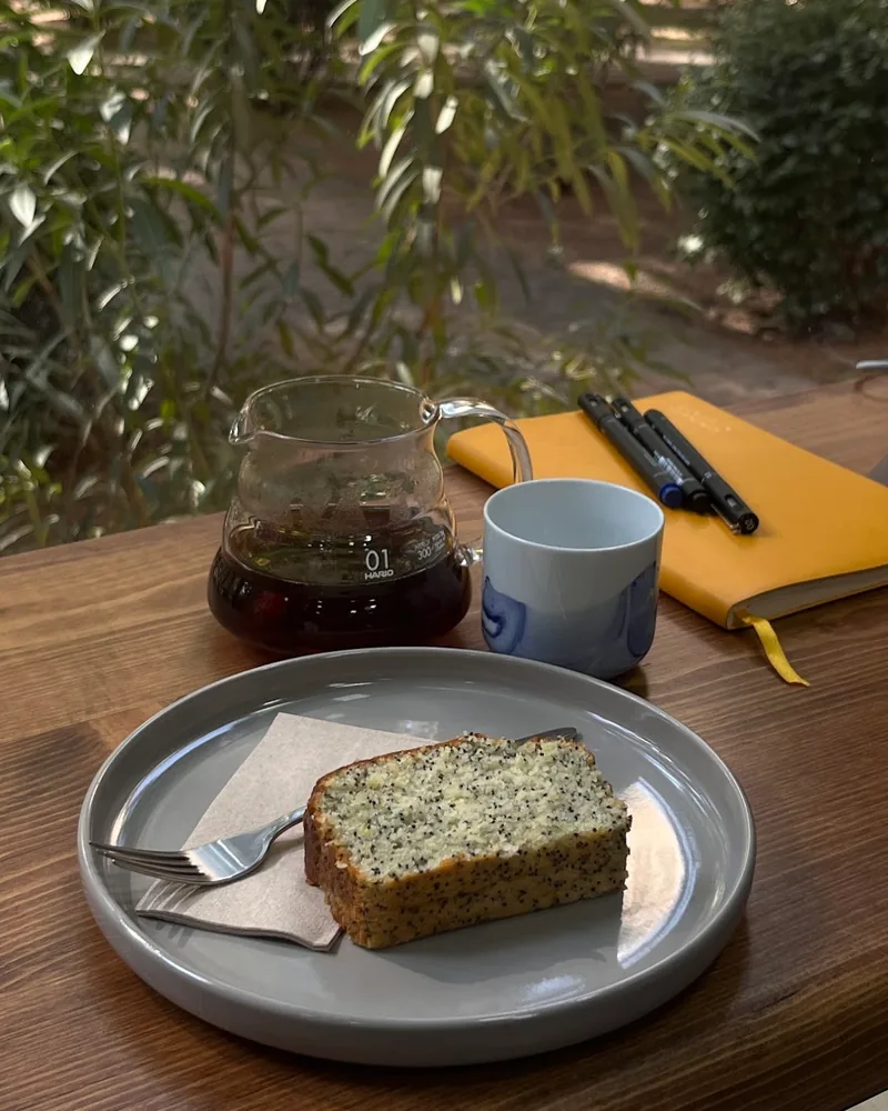 Slice of poppy seed cake on a plate with filter coffee server at The Little