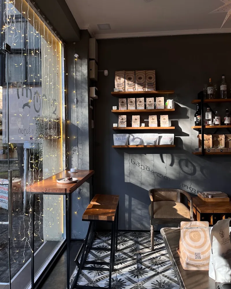 Cafe seating area next to window with shelves of coffee at The Little