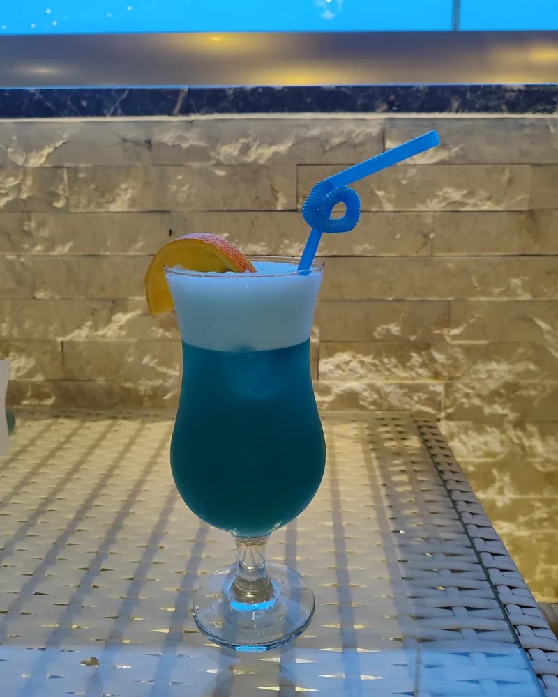 Blue cocktail with foam and an orange slice at Tiffany Bar & Terrace