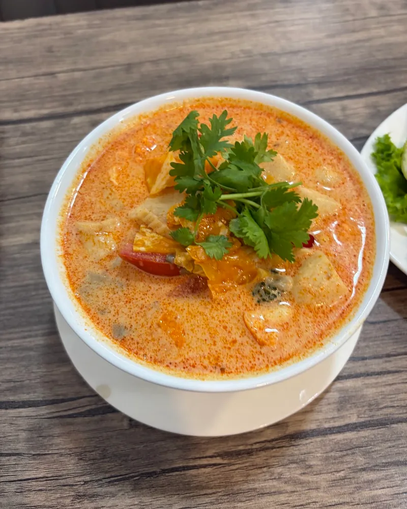 Tom yum soup in a white bowl at Tom Yum