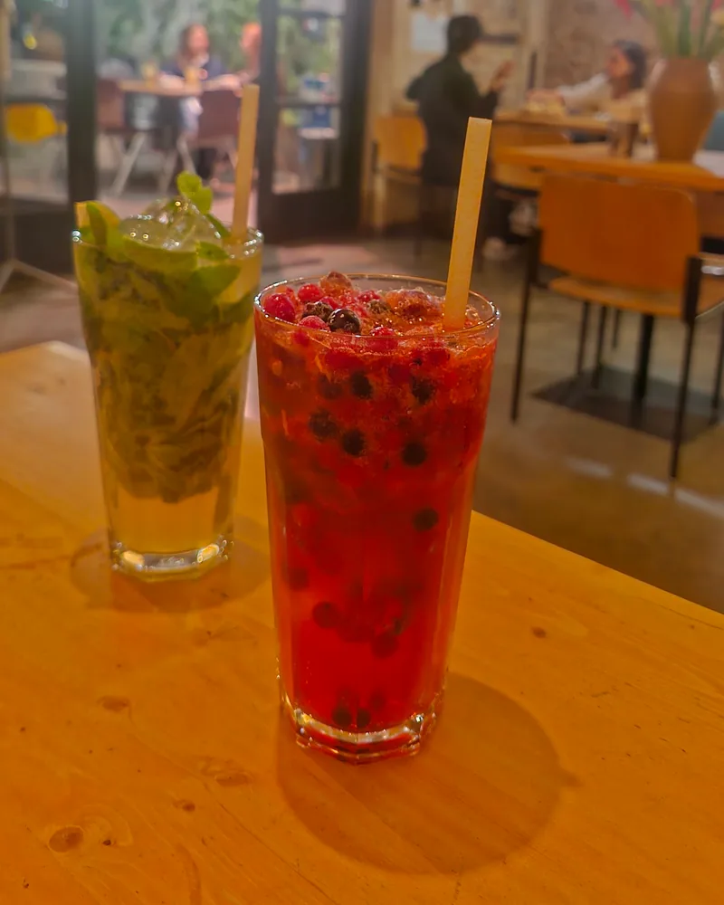 Berry cocktail and a mojito on a wooden table at Tone