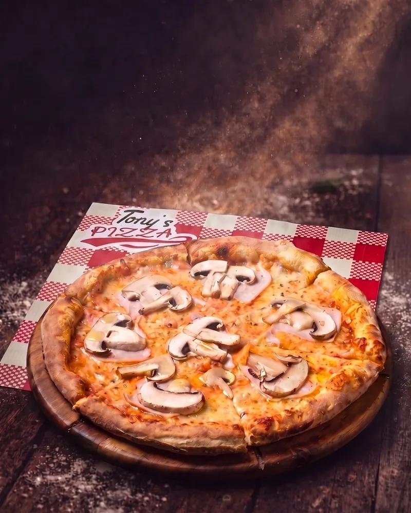 Mushroom and ham pizza on a wooden peel at Tony’s Pizza