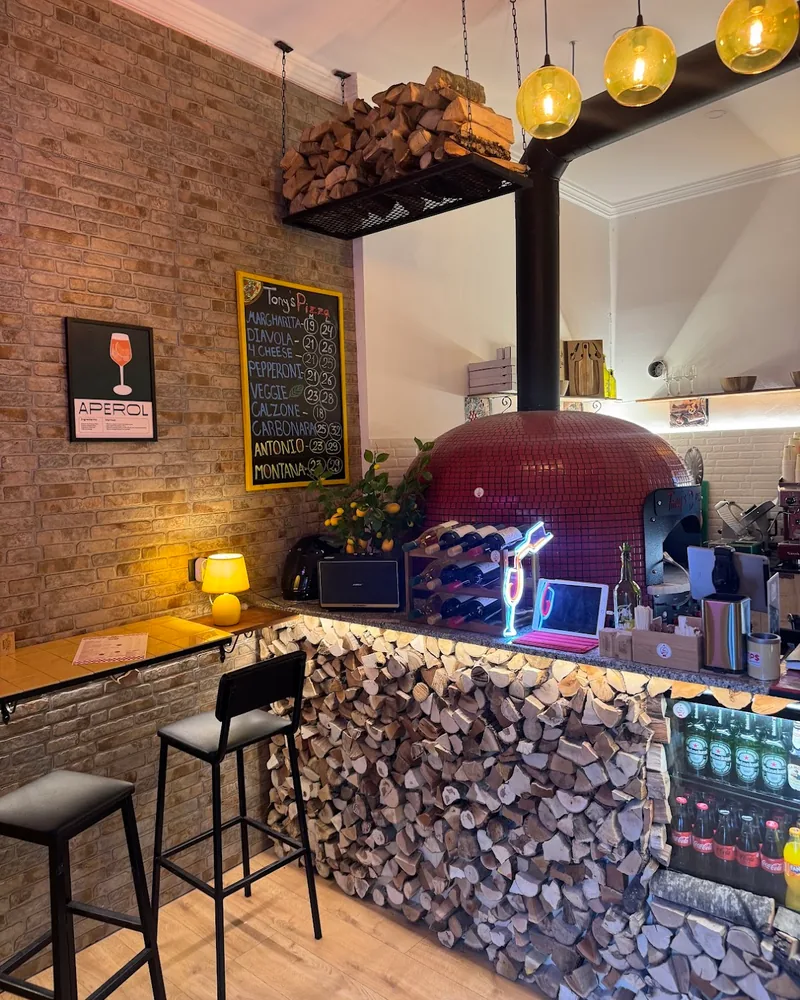 Pizza oven and wood-stacked counter with bar stools at Tony’s Pizza