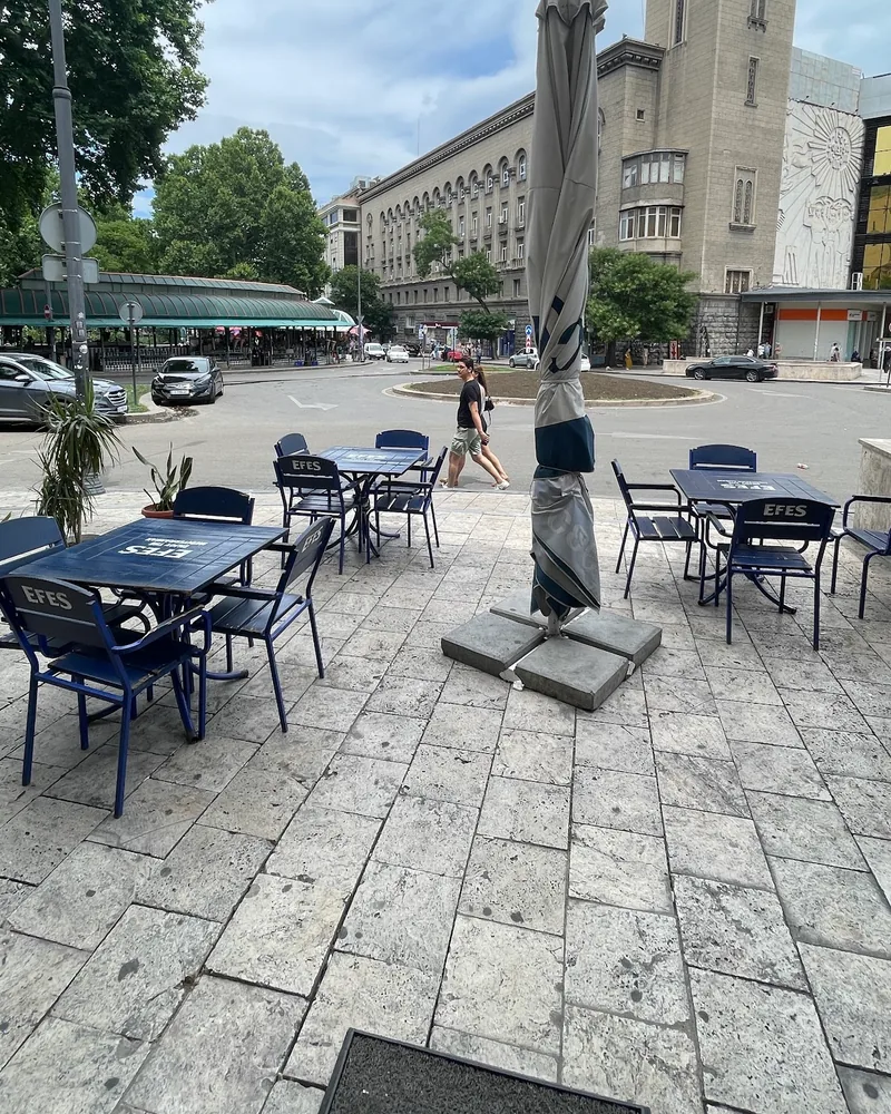 Outdoor patio seating with blue branded chairs and square tables at Town