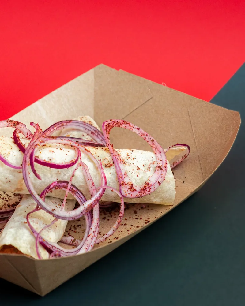 Kebab wraps with red onion in a cardboard tray at Tsetskhli Ainto