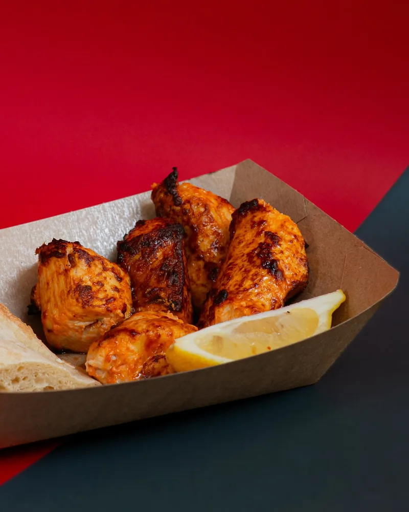 Chicken skewers with bread and lemon in a paper tray at Tsetskhli Ainto