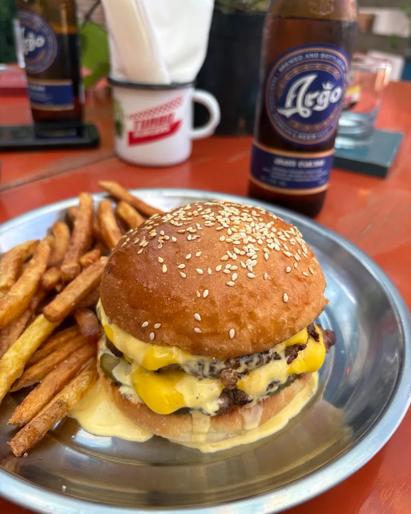 Cheeseburger and fries on a metal plate with bottled beer at Turbo Burgers