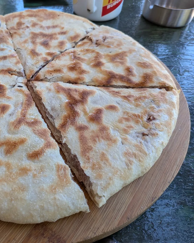 Kubdari sliced on a wooden board with pickles at Turbo Burgers