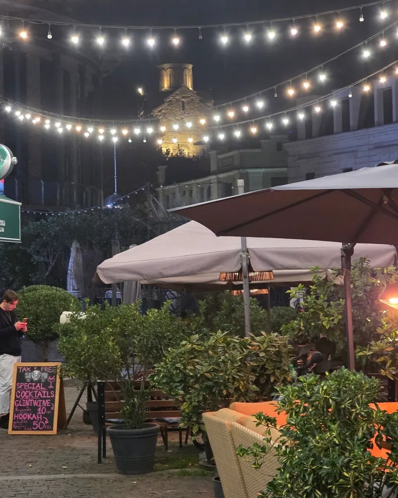 Outdoor patio seating with umbrellas and string lights at Unholy Bar