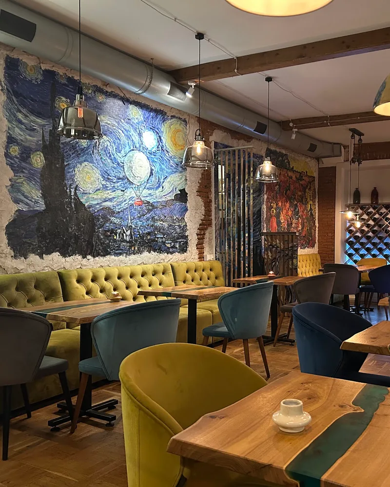 Dining room with starry night mural and wooden tables at Van Goghi