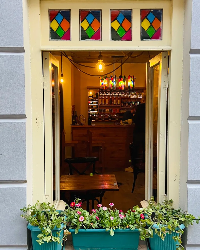 View into the cosy bar interior framed by a window with stained glass and flowers at Vinissimo