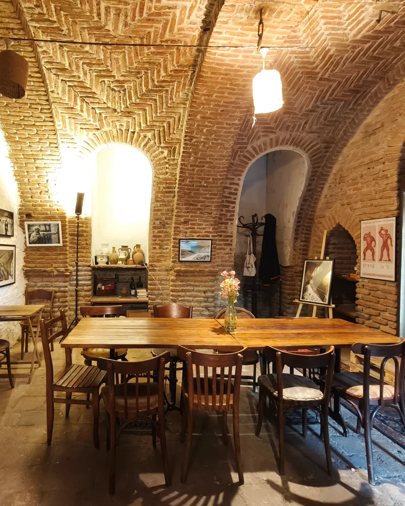 Brick vaulted wine cellar dining room with wooden tables at Vino Underground