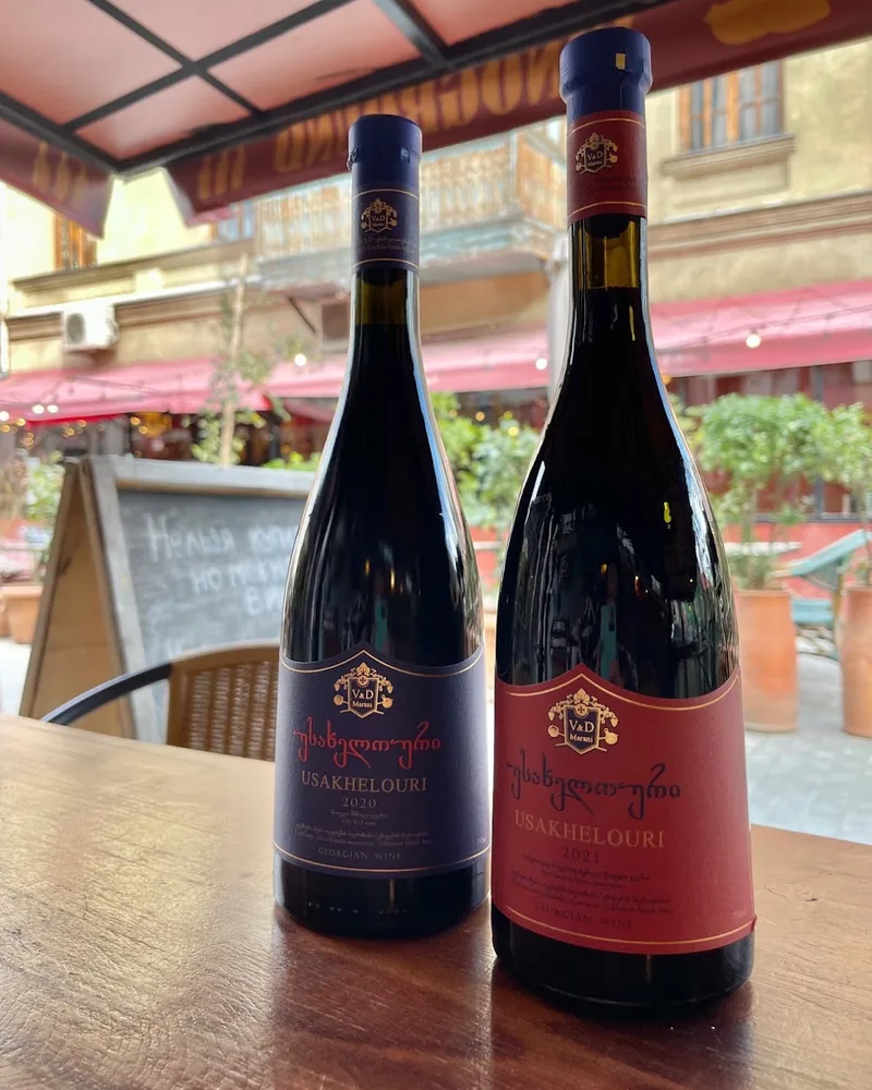 Two bottles of Usakhelouri red wine on an outdoor table at Vinoground