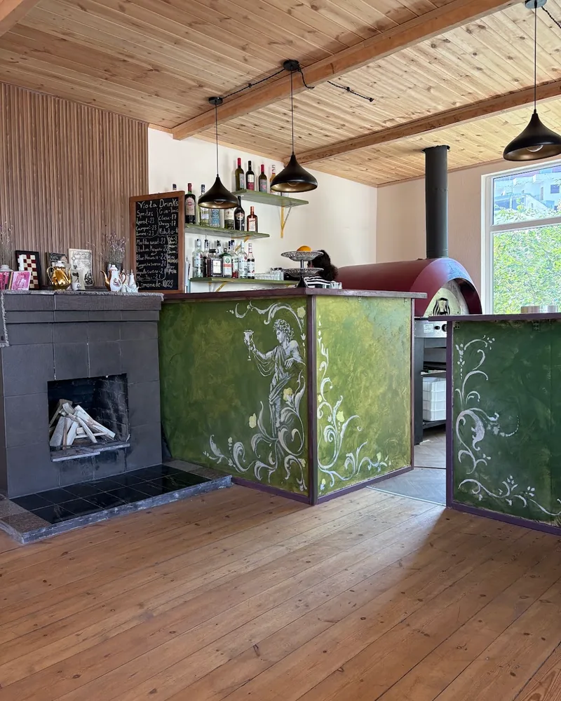 Indoor dining room with green painted bar counter and fireplace at Viola