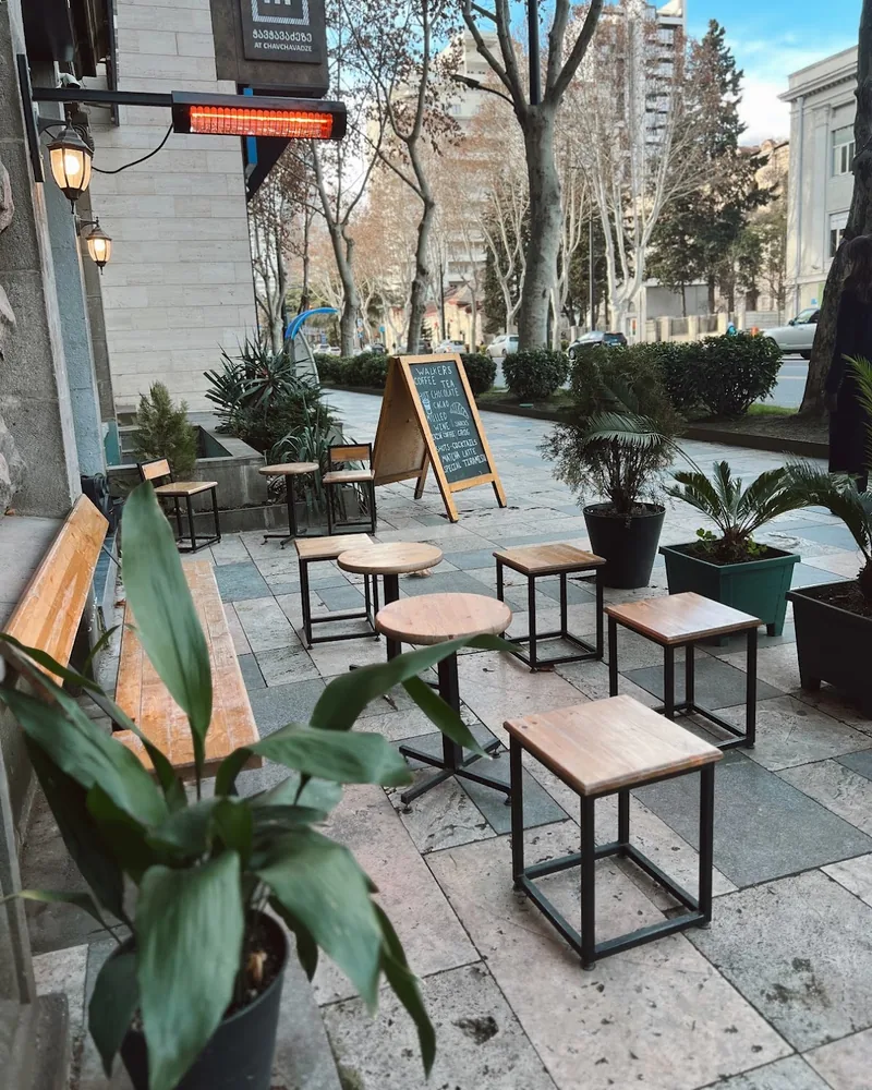 Sidewalk seating with wooden stools and small round tables at Walkers Espresso Bar