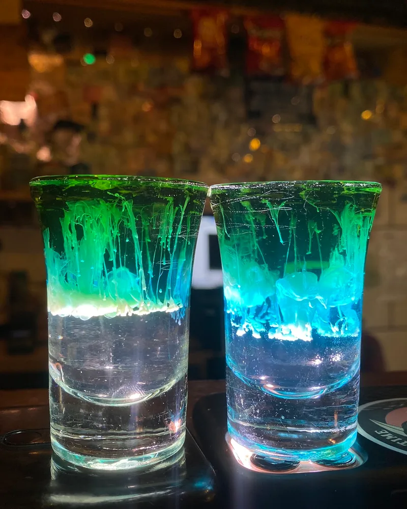 Two layered shot cocktails illuminated by phone screens at Warszawa