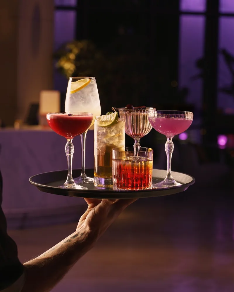 Cocktails on a serving tray carried by a server at Weather Report Sky Bar