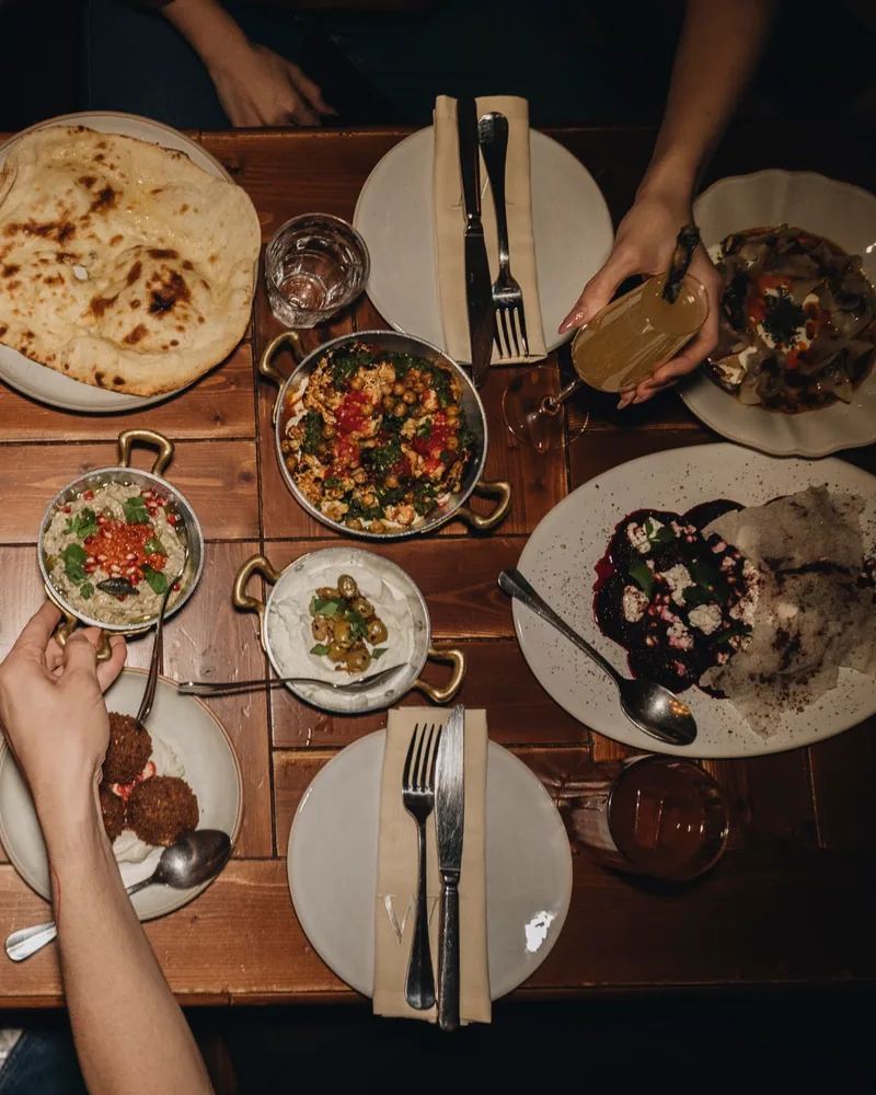 Spread of middle eastern mezze and flatbread on wooden table at Weller