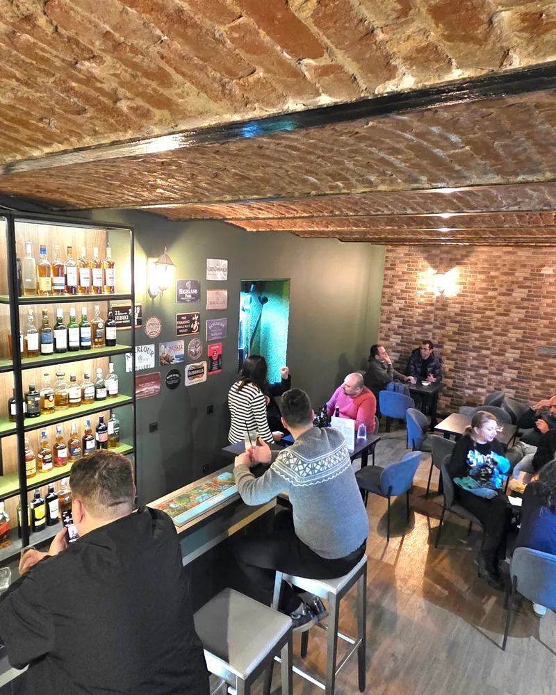 Vaulted brick bar room with bottle shelves and seating at Whisky Club Bar