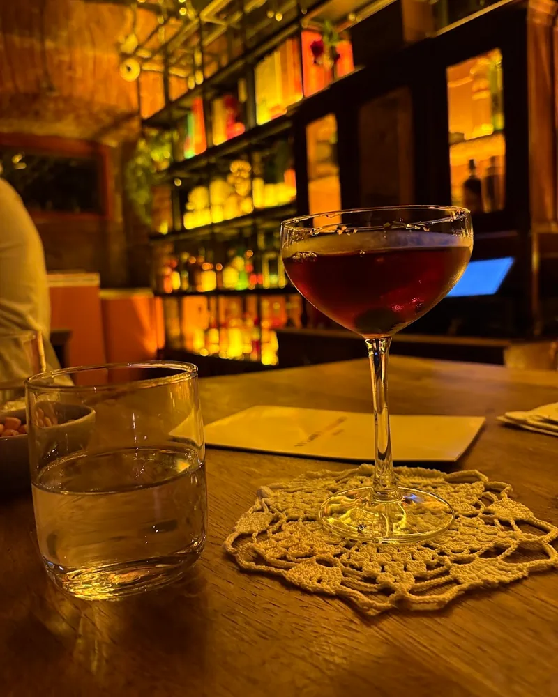 Dark cocktail in a coupe glass on a crocheted coaster at Whisky Library