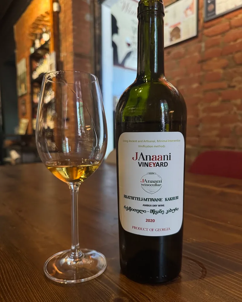 Amber wine in a glass next to a janaani wine bottle at Wine Boutique