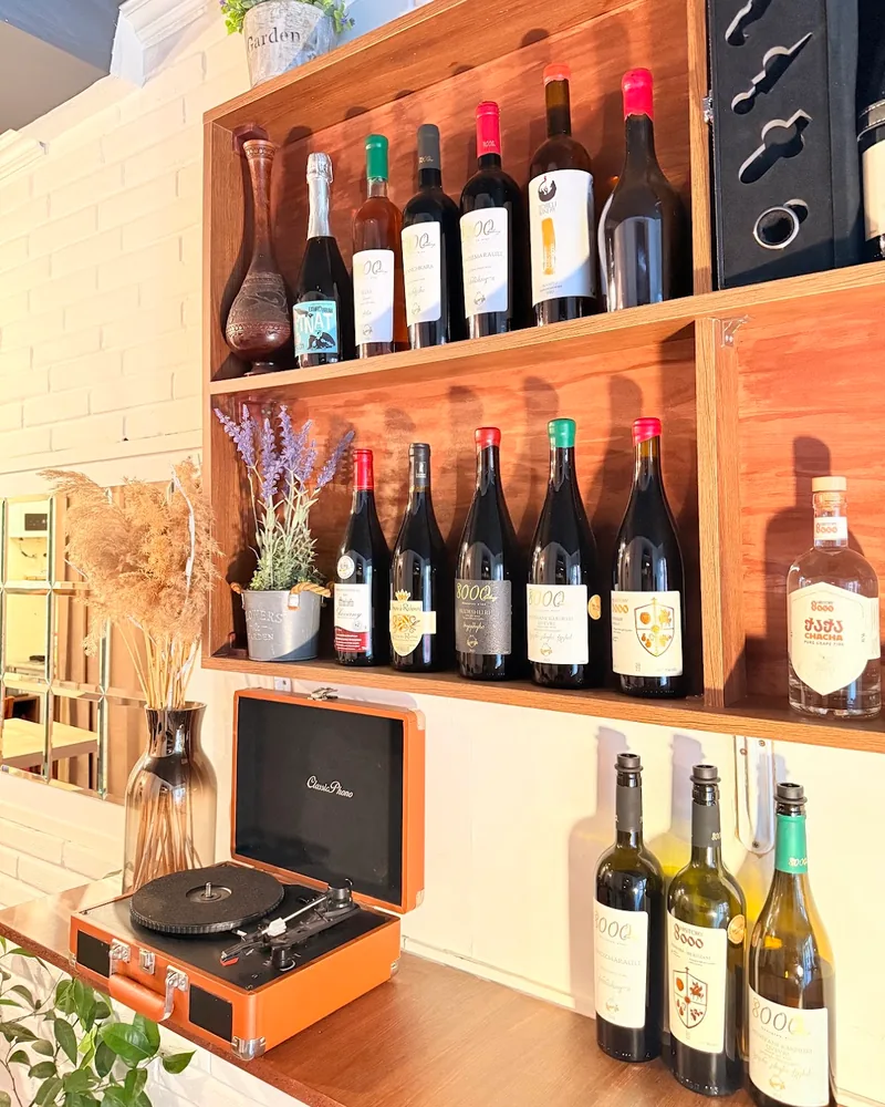 Wooden shelves with wine bottles and a record player at Meghvine