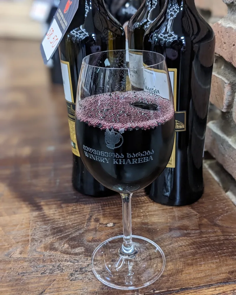 Red wine in a branded tasting glass at Winery Khareba