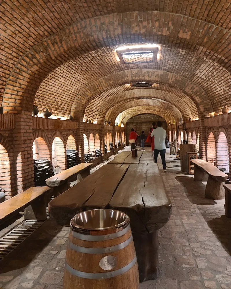 Vaulted brick wine cellar tunnel with tasting tables at Winery Khareba