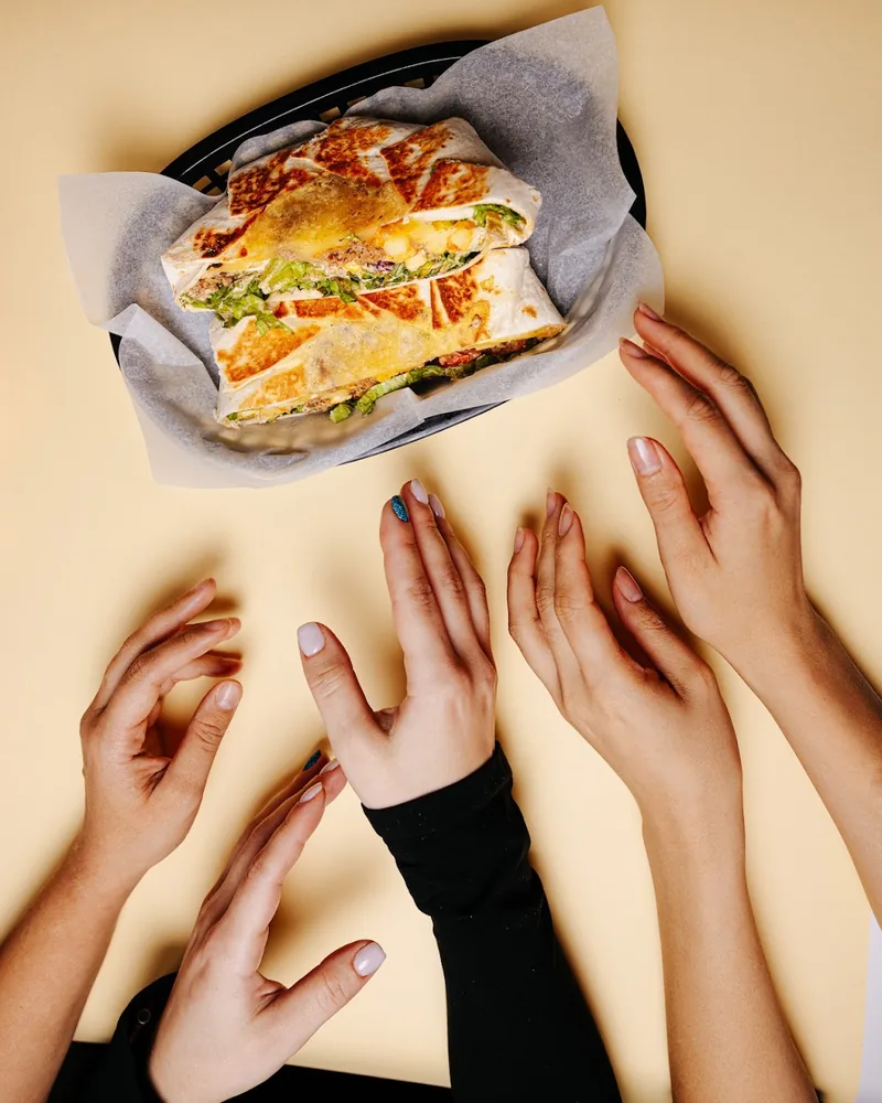 Toasted wrap cut in half in a basket with reaching hands at Wrap Master