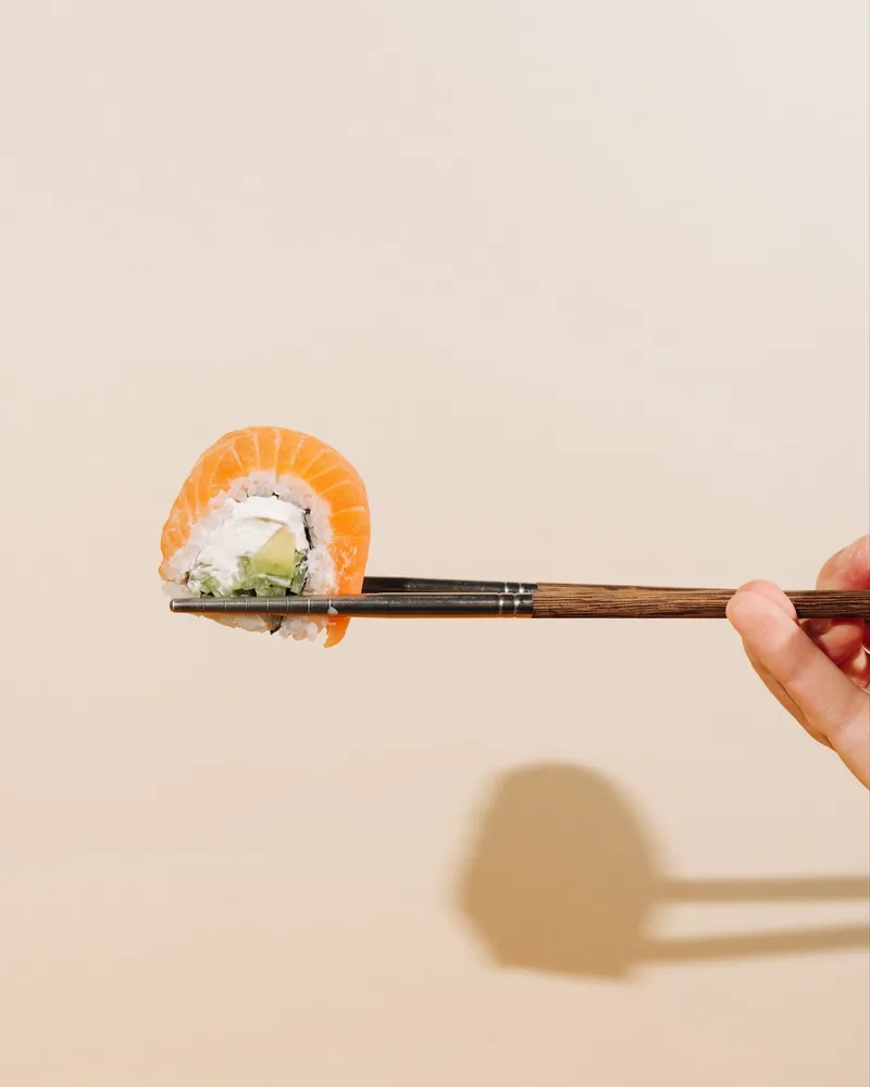 Salmon sushi roll held in chopsticks at Yuki Yume