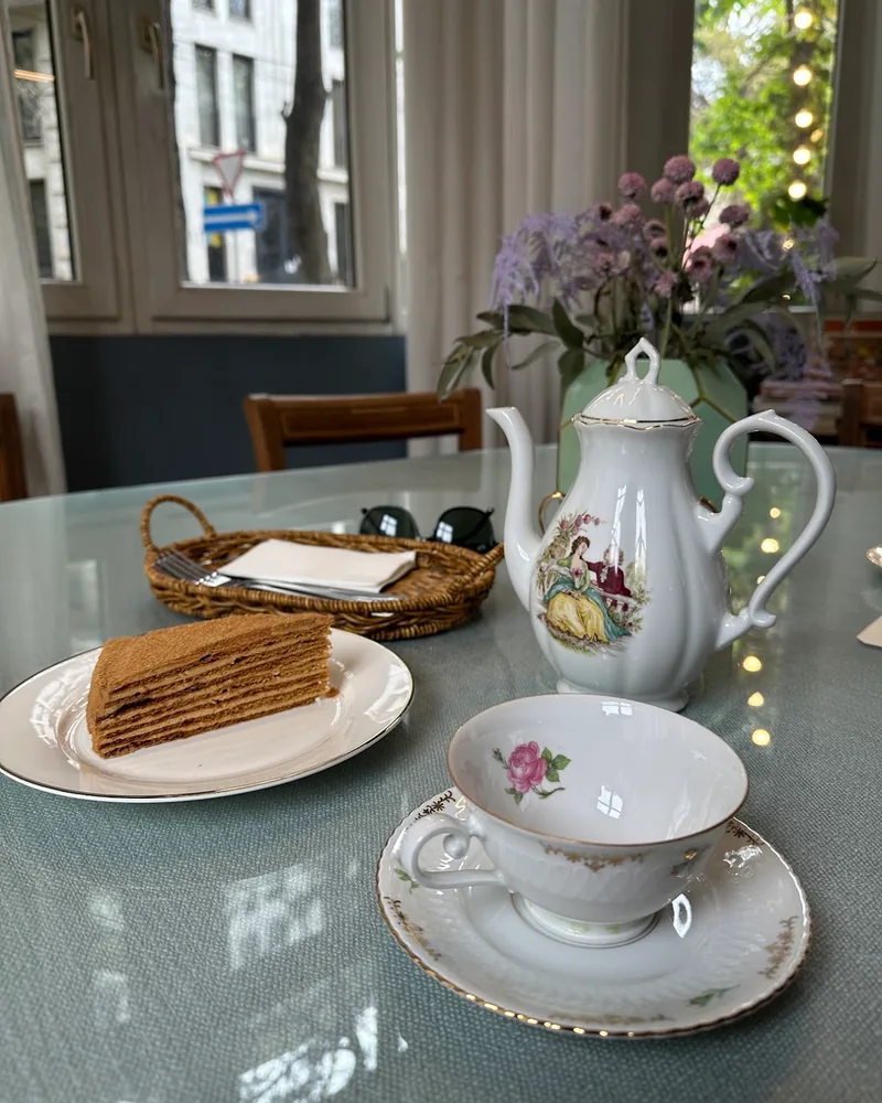 Tea set with porcelain teapot, teacup, and layered cake at Zilina Cafe