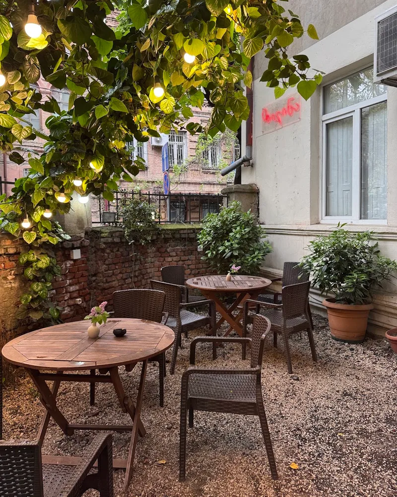 Outdoor courtyard seating under a leafy canopy at Zilina Cafe