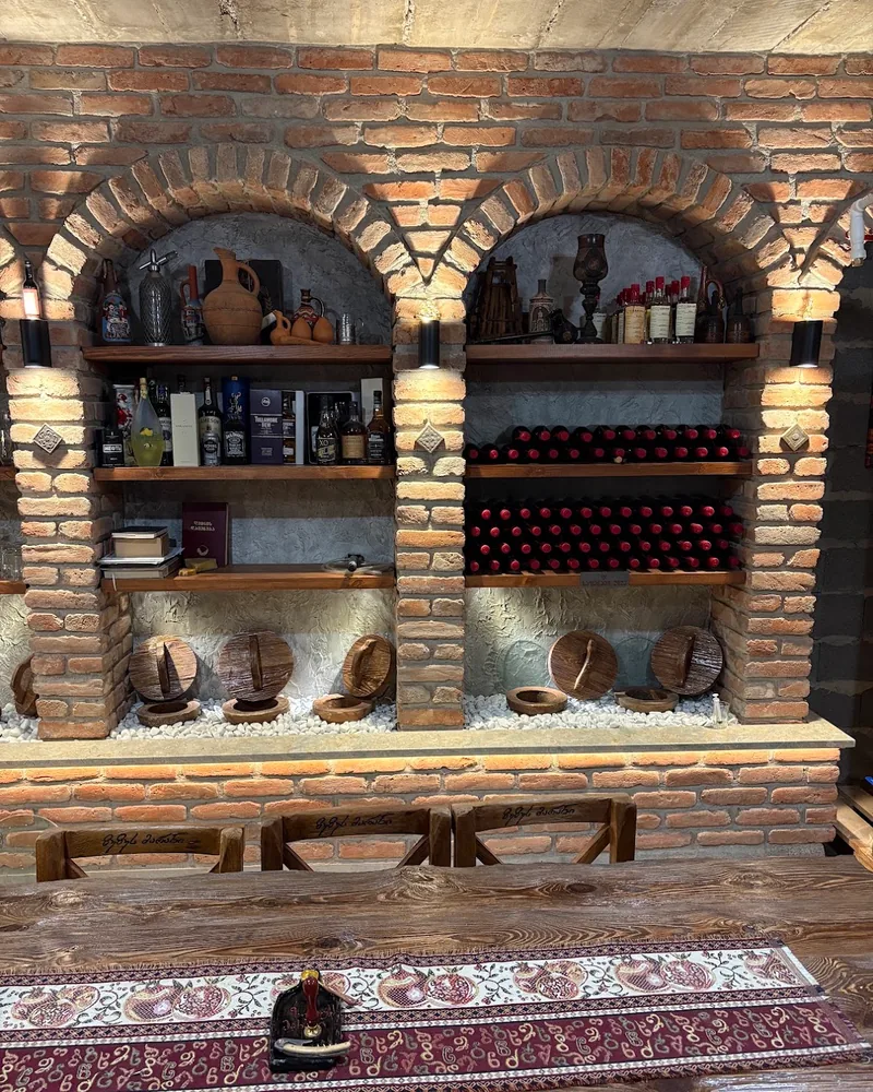 Brick arched wine cellar wall with bottles and qvevri covers at Zuzu's Winery